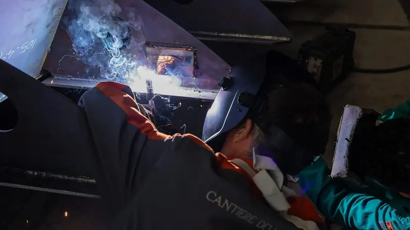A yard welder completes a seam on the RAW 110's steel keel during construction.