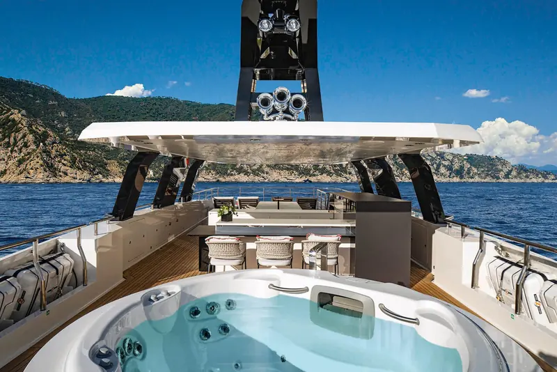 An aft sundeck shaded by a fixed hardtop structure, a plunge pool set into the deck beneath it.