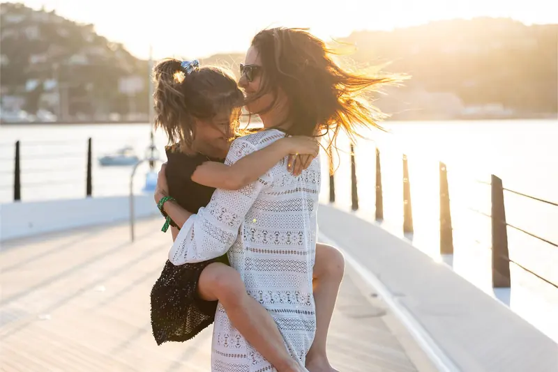 A mother carries her daughter along the aft swim platform, the informal family framing CRN used across Rio's delivery photography rather than a staged owner portrait.