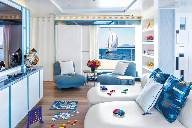 A children's playroom on board, toys and a board game left out on the floor beside built-in banquette seating in blue and white.