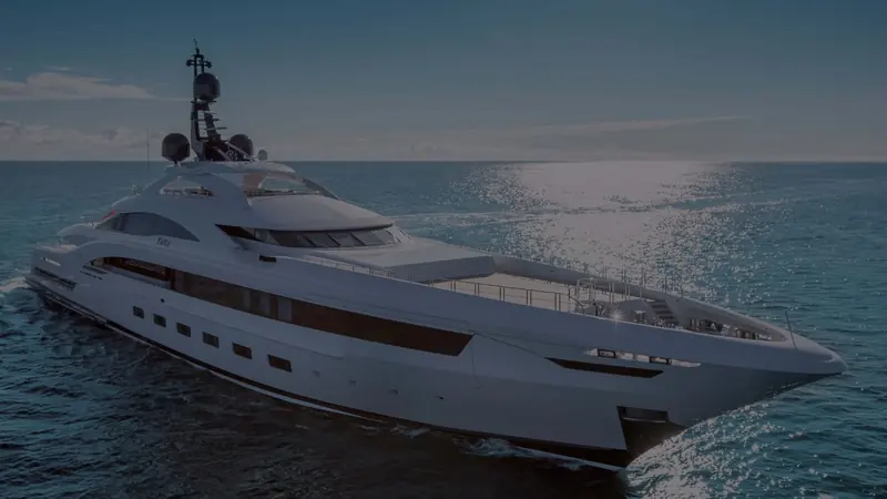 Yalla photographed broadside at dusk, the hull rendered in near-silhouette against a darkening sea.