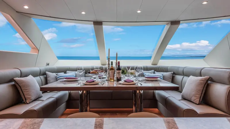 The pilothouse dining area, set for a formal meal with a clear view forward through the raised helm's windows.