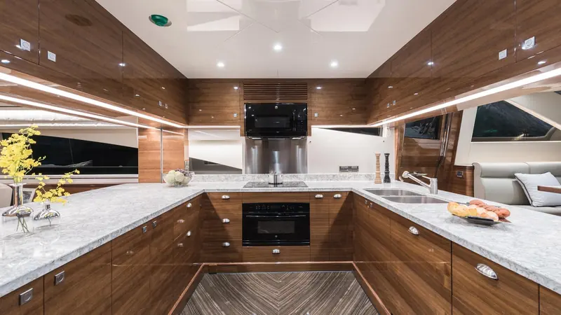 The galley, finished in the same dark wood as the saloon with granite counters and full-size appliances rather than a compact yacht galley.