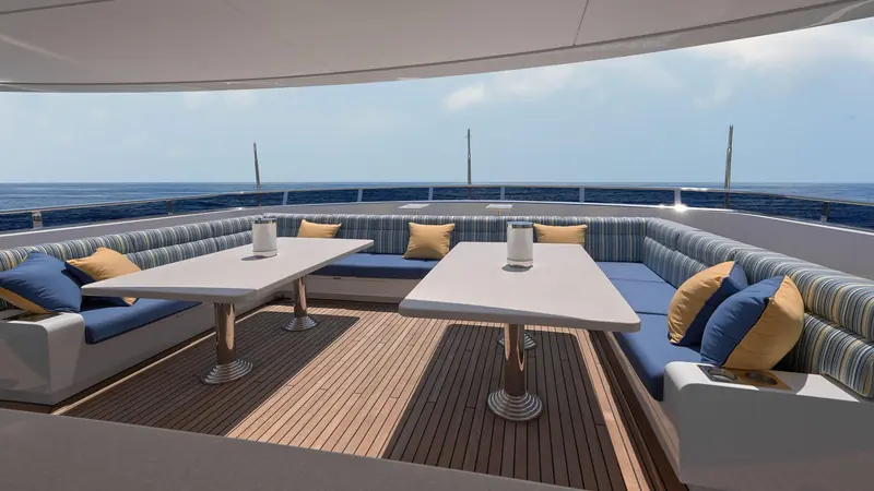 An alfresco dining nook on the upper deck, shaded by the hardtop and fitted with fixed banquette seating.