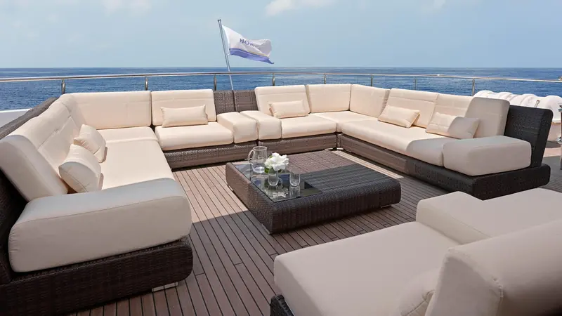A wraparound deck sofa on the sundeck, upholstered in weather-resistant wicker for long stays at anchor.