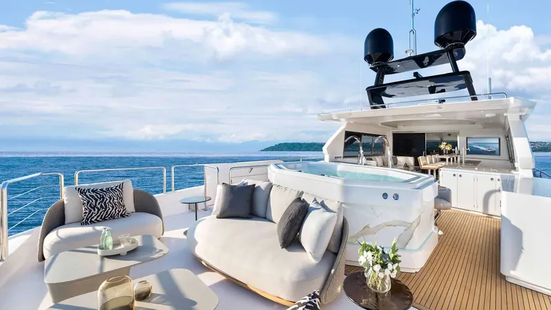 A shaded upper deck lounge next to the built-in spa pool, with an alfresco dining table forward.
