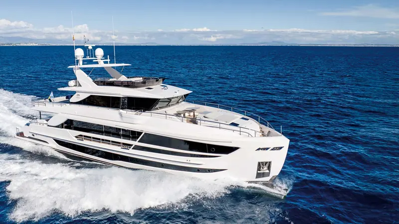 Running at speed with a full bow wave, showing the hull's flare and the tender garage door aft.