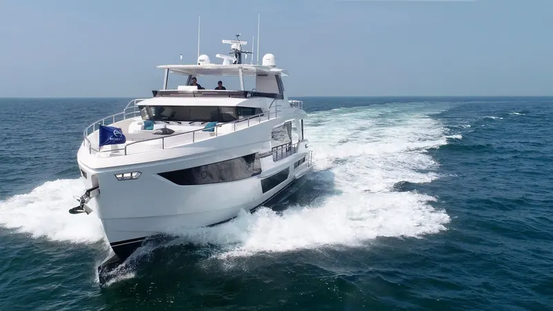 Underway from a lower angle, the flybridge overhang shading the aft deck seating beneath it.