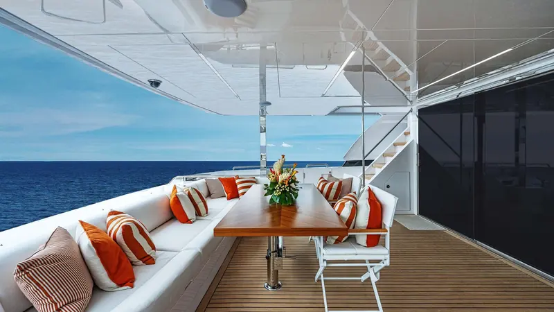 The aft cockpit dining table, striped cushions and open rail rather than solid bulwarks.