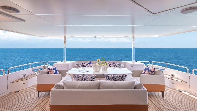 The main aft deck lounge sits deep under the overhang, shaded through the middle of the day.