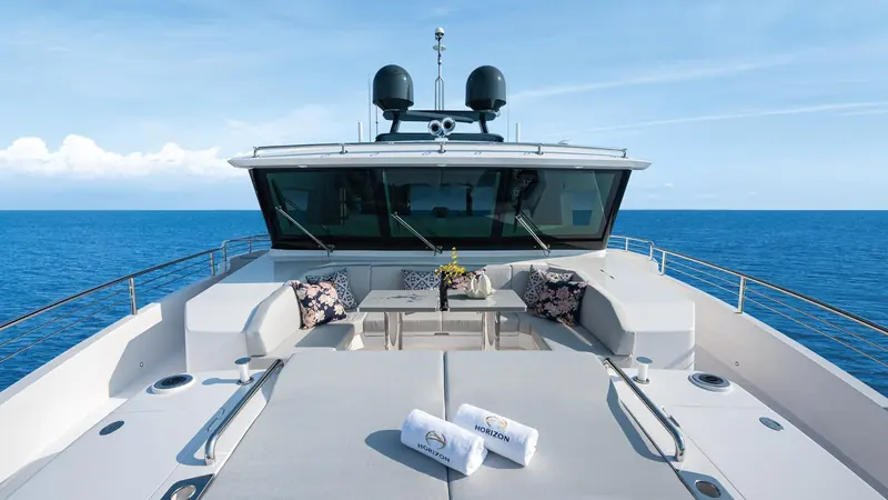 Foredeck seating faces aft towards the pilothouse glass, the twin radomes mounted above it.