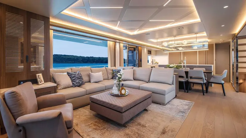 The main deck salon opens into the galley and dining area, with a full window wall giving unbroken views to the water.