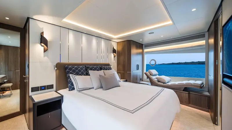 The master stateroom with a forward-facing window seat, finished in dark walnut against pale upholstery.