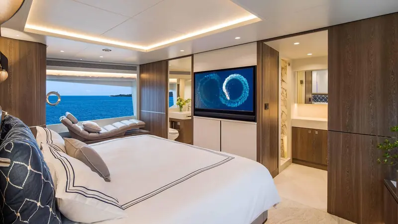 A second stateroom with an en suite bathroom visible through the open door, fitted with a wall-mounted television.