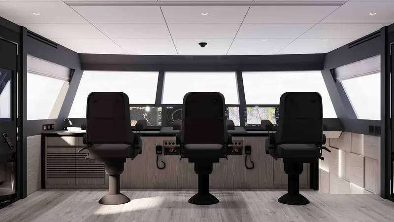 Three helm seats face a bank of multifunction displays and VHF handsets in the enclosed wheelhouse, with live chartplotter data visible on screen.