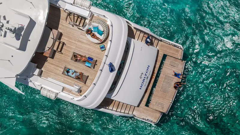 The sundeck seen from directly above, with three loungers set into the teak and the Horizon branding visible on the beach club door below.