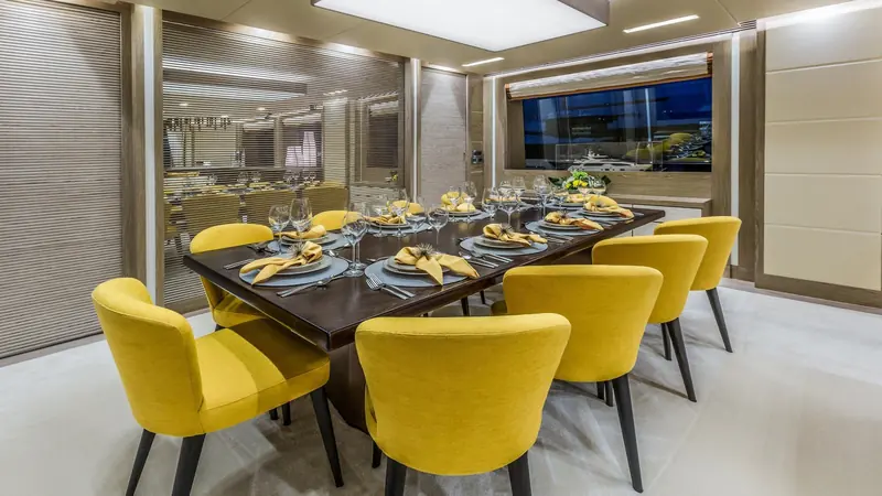 The formal dining table seated for eight, positioned forward of the salon with sea views on both sides.