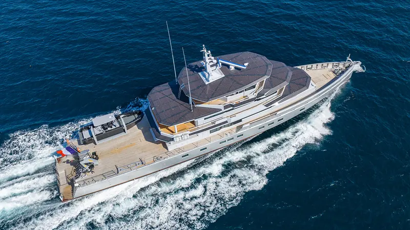 Canoa underway, seen from above: the aft deck tender, solar panels on the wheelhouse roof and French ensign.