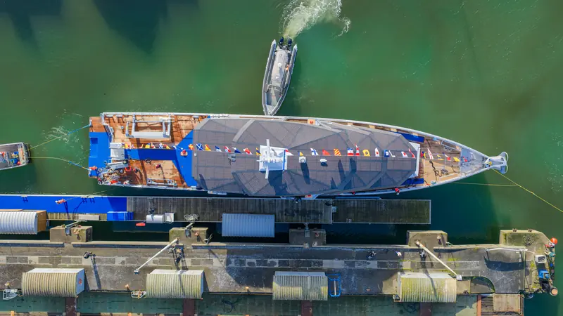 Overhead view of Canoa dressed for her launch in the dock at Concarneau, a workboat standing by.