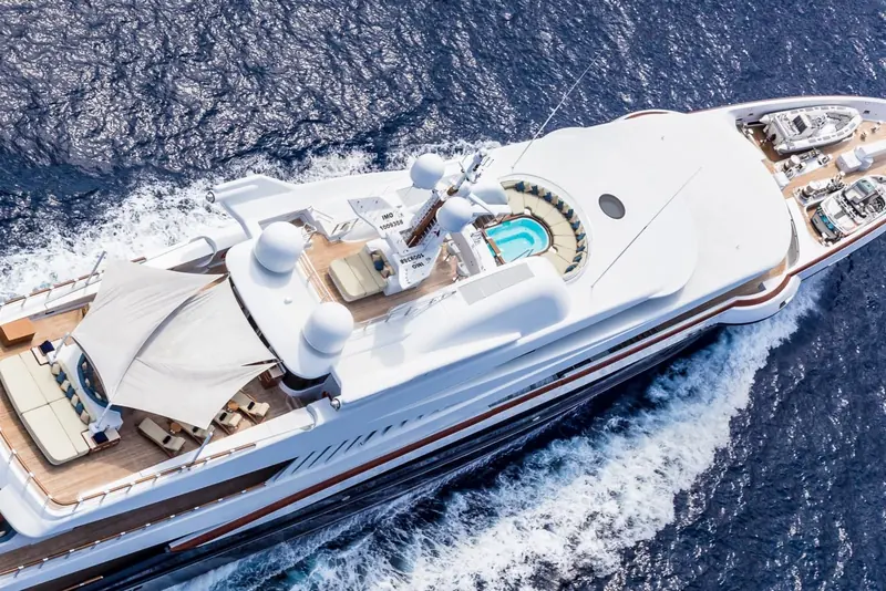 An aerial view running at speed, showing the full deck layout from the sundeck pool to the bow.