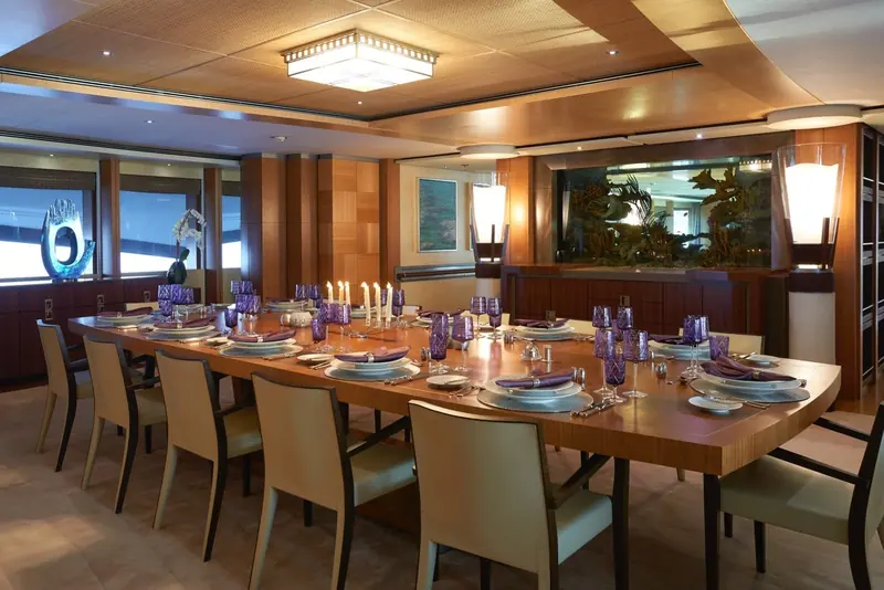 The formal dining room, a full table set beneath a coffered ceiling and a built-in aquarium.