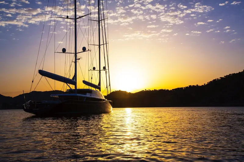 Aquijo silhouetted at sunset, masts and standing rigging outlined against the sky.