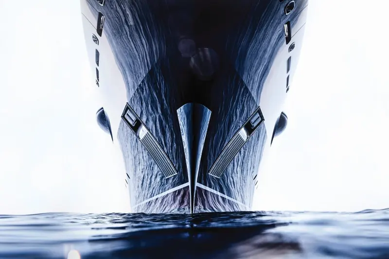 A low, water-level view of the stem wave breaking off the black topsides.