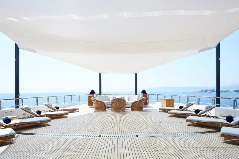 The foredeck lounge, shaded by a retractable sail awning and laid out with a full circle of loungers and a wraparound sofa.