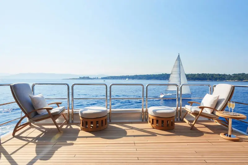 Aft deck seating with a classic sailing yacht passing astern in the anchorage.