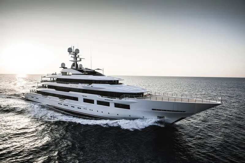 Underway at golden hour, her raised foredeck helipad and full-beam bridge deck visible in profile.
