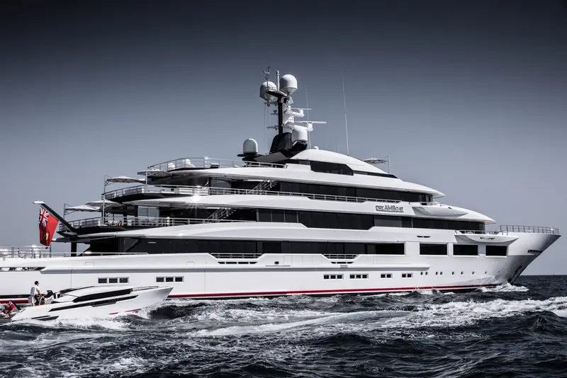 Escorted by her custom tender against a darkening sky, the Cayman ensign flying aft.