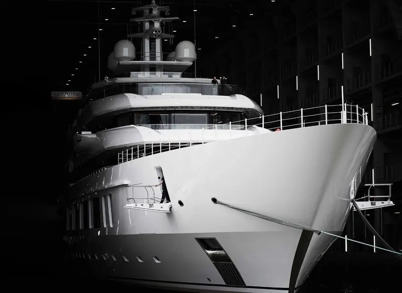 Inside Oceanco's covered build hall, moments before float-out, crew still aboard the bow.