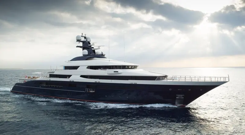 Tranquility underway at dusk, her navy-blue hull and full-beam sundeck silhouetted against a breaking sky.