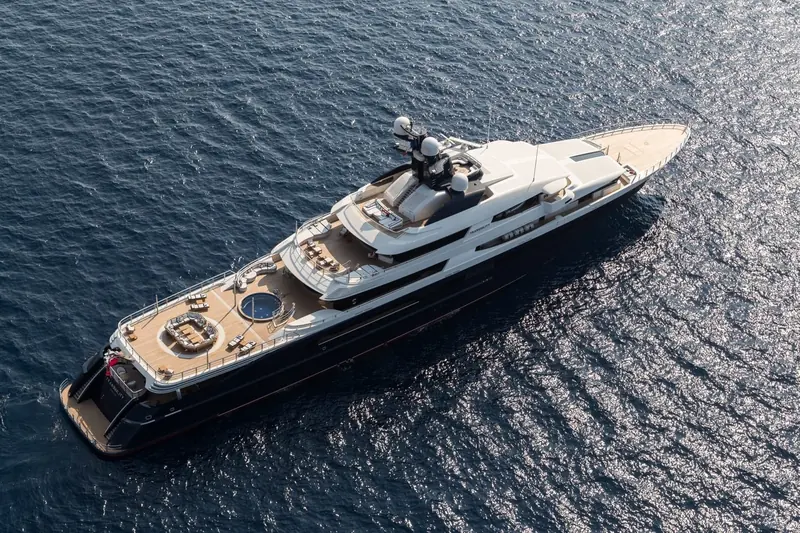 Aerial view of Tranquility at anchor, her name visible on the transom above twin swim platforms and a full deck of alfresco seating.