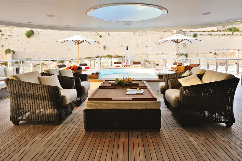A shaded deck lounge set against a stone quay, umbrellas up against the midday sun.