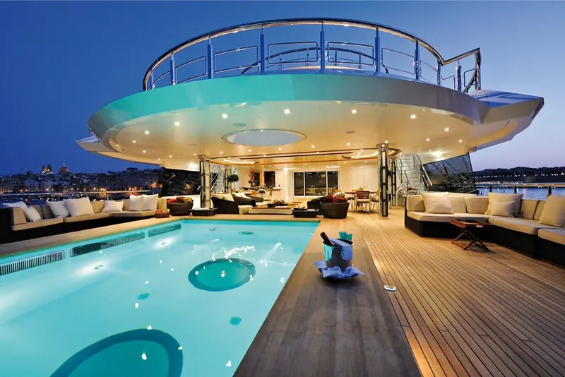 The sundeck pool set beneath a sweeping overhang, tender parked alongside on the swim platform.