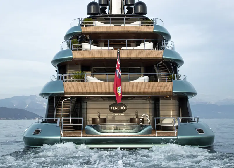 The transom at speed, nameplate lit in bronze above a fold-out swim platform pool that retracts flush with the deck underway.