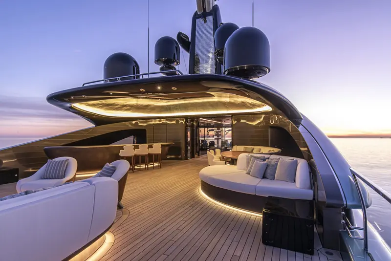 The bridge-deck aft lounge sits under a sweeping glass overhang, its curved sofa built around the line of the hull rather than set square to it.