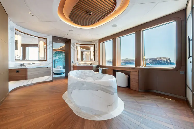 The owner's bathroom centers on a free-standing marble tub carved to look poured rather than cut, set on its own inlaid floor medallion.