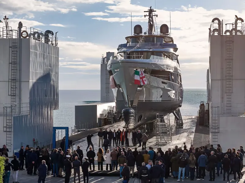 Spribe's naming ceremony on the slipway: her hull and superstructure carry the Italian and Georgian flags, a nod to the owner's home port before the launch into the Ligurian Sea.