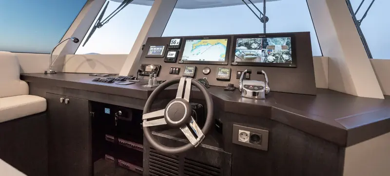 The helm station with twin Raymarine multifunction displays, engine-room camera feeds and analogue backup instruments.