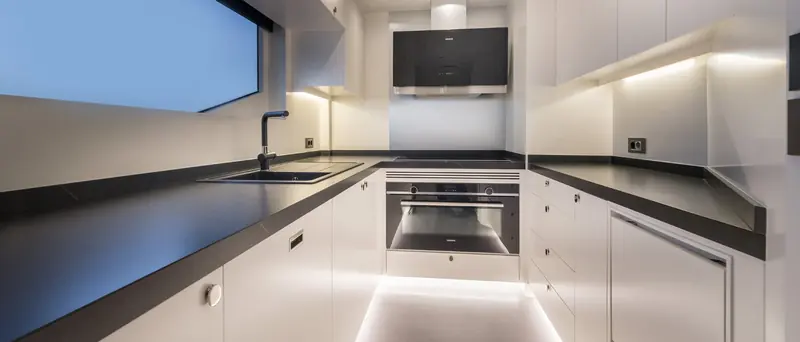 The galley below deck, finished in gloss white with Siemens appliances and integrated LED plinth lighting.