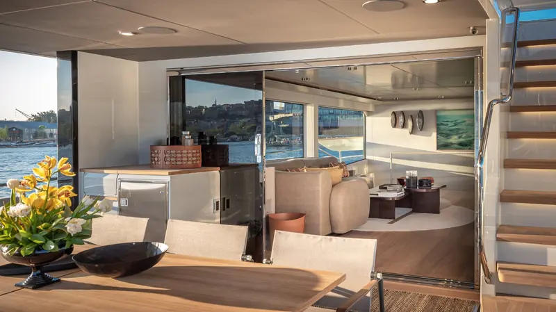 The main deck salon opens fully to the aft cockpit dining table, with the Bosphorus and the far shore visible through the glass.