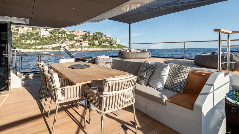 The aft cockpit dining table with a coastal town in the background, set up for al fresco meals rather than a formal saloon dinner.