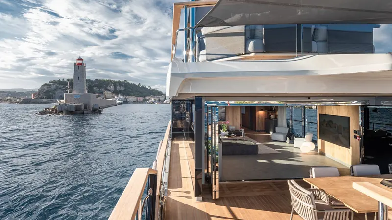 Passing a Riviera harbour lighthouse, the folding glass doors that join the aft deck to the saloon fully open.