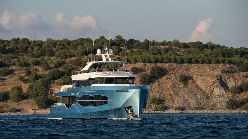 A second hull in a teal livery rather than white, the same diamond window cut visible on the bow either way it is painted.