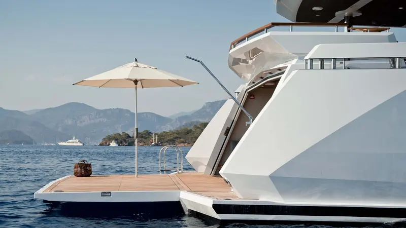 A fold-out beach-club platform at the stern extends the swim deck well beyond the transom, shaded by its own side awning.