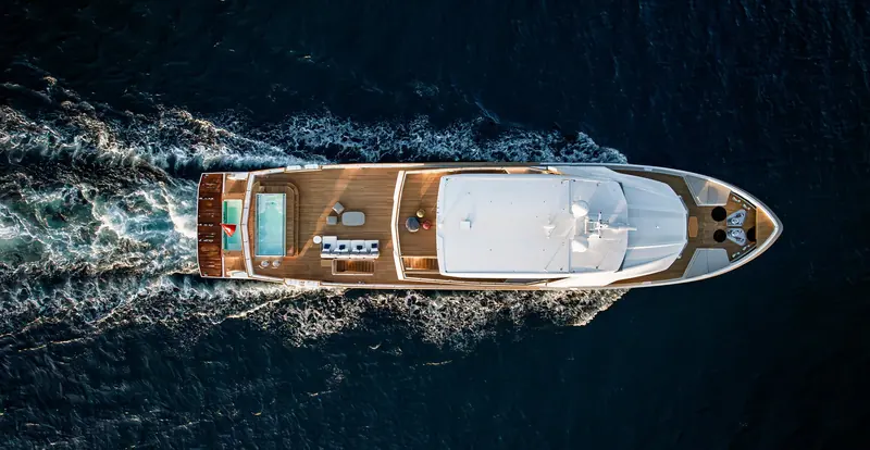 Running bow-on, the foredeck sun pad and starboard-side pool are both in near-constant shade from the flybridge overhang above them.
