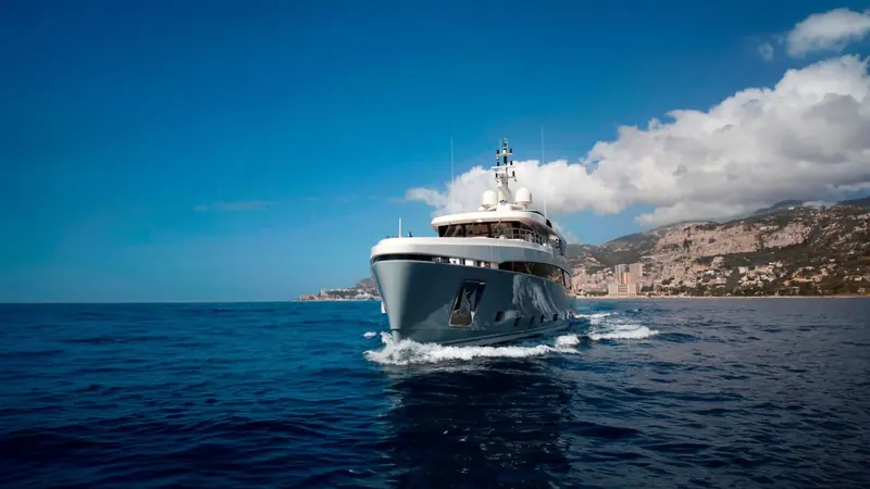 Bow-on against the Monaco coastline, the boat's beam looks disproportionately wide for its length, a deliberate trade for interior volume over outright speed.