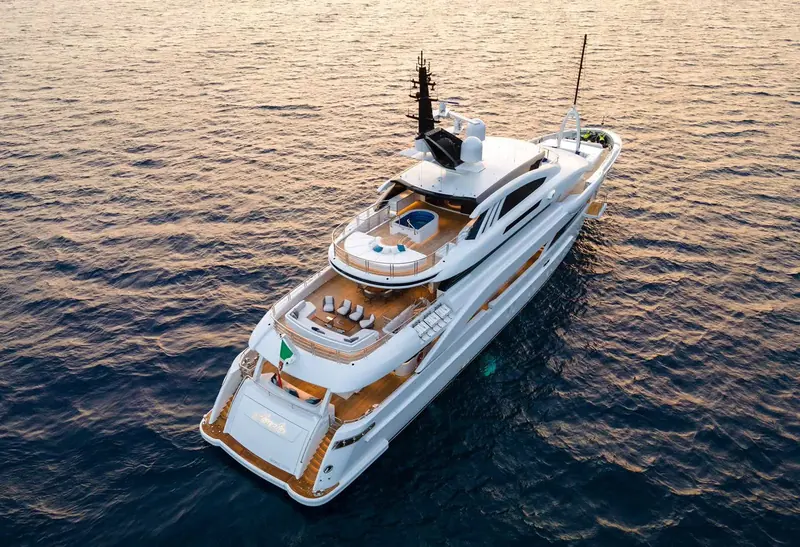 An aerial view under way showing the full sundeck layout aft of the bridge, with a spa pool and shaded lounge kept separate from the open sunbathing area forward of it.